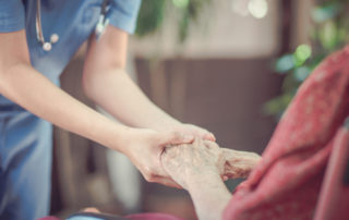senior holding hands with nurse