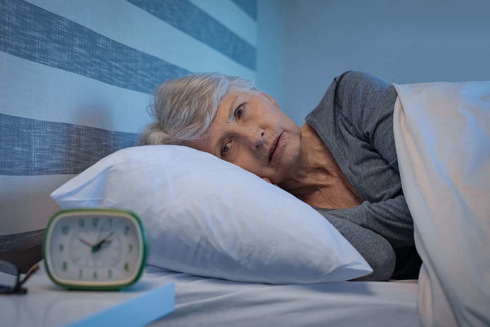 Oakleigh Macomb senior woman looking at clock in bed can't sleep