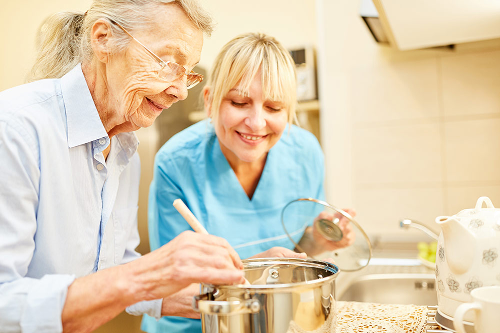 Oakleigh of Macomb Senior Living senior woman with caregiver cooking