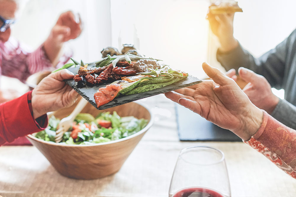 Hands passing plate of health grilled vegetables