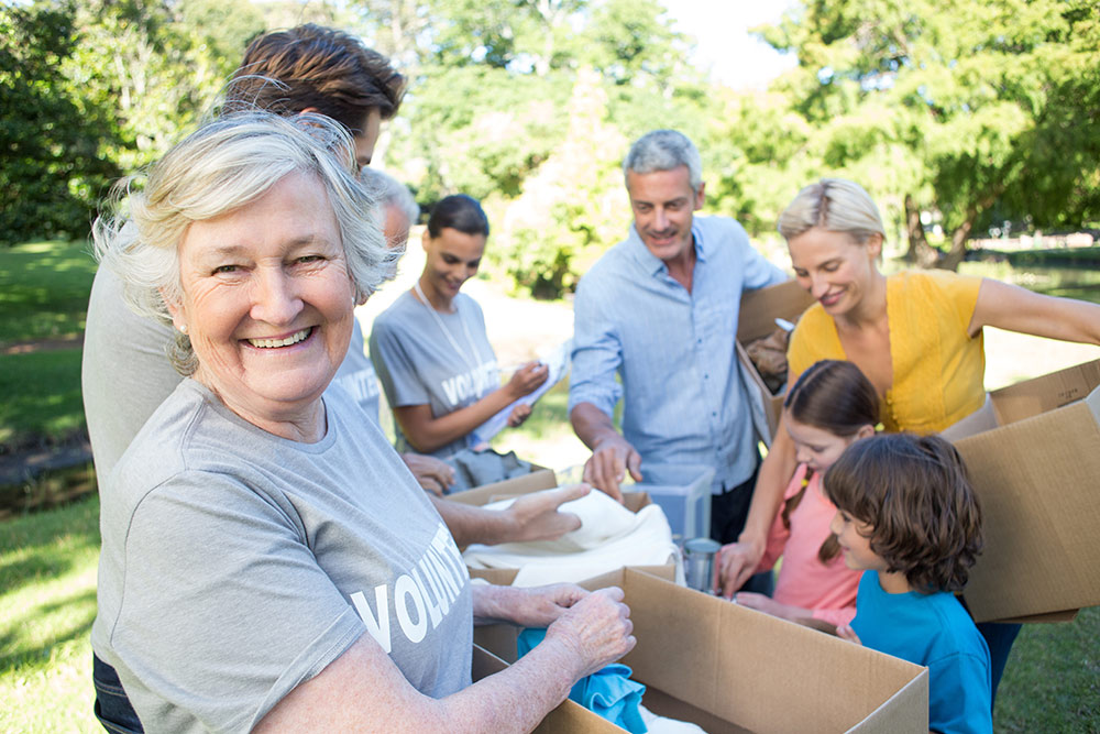 Senior woman in volunteer shirt working with other people outside