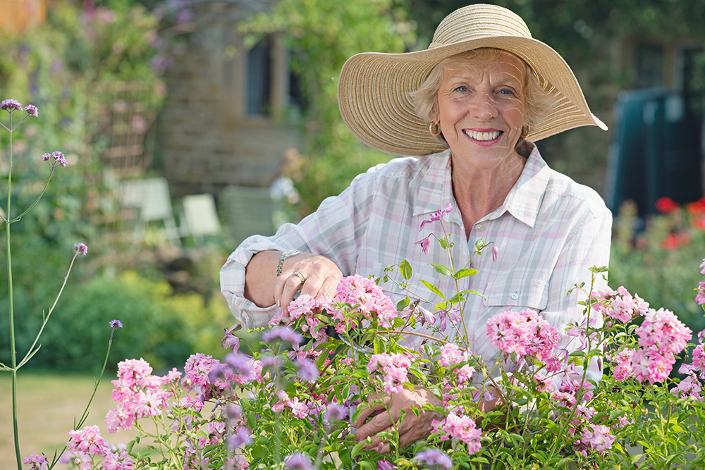 Senior woman smiling and gardening outside in memory care community