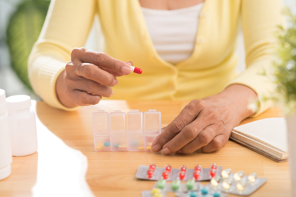 Close up of senior woman's hands organizing medication in pill organizer