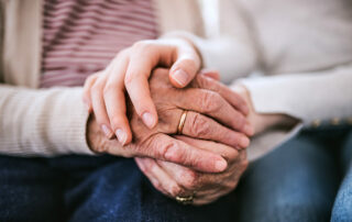 Caregiver and senior holding hands