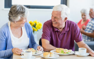 Senior couple eating breakfast at table in senior housing community