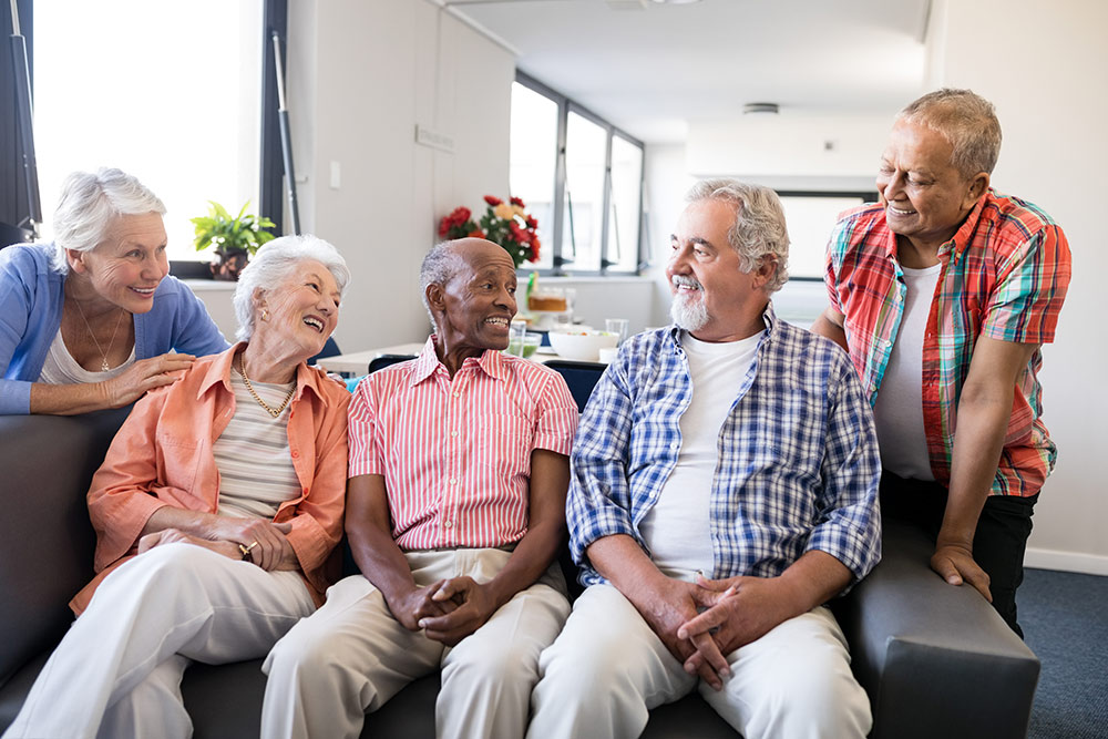 Happy seniors on couch talking in senior living community