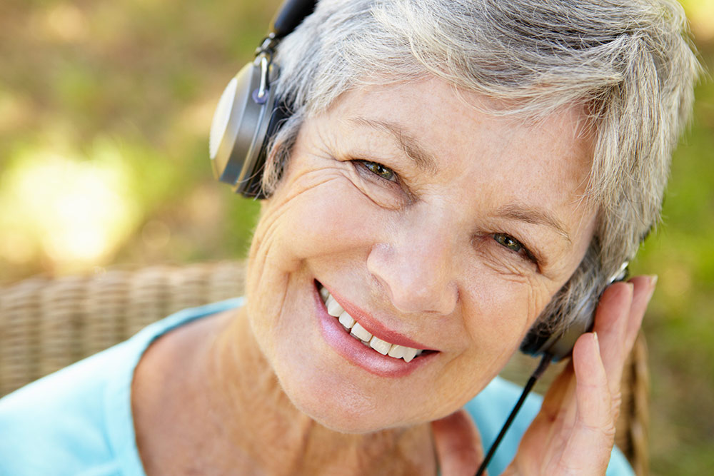 Happy senior woman smiling while listening to music with headphones on