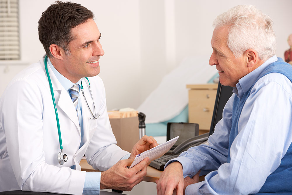 Senior man sitting in doctors office talking with doctor