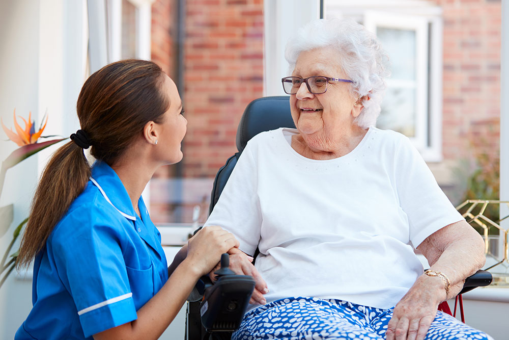 Senior woman sitting down with caregiver in assisted living community