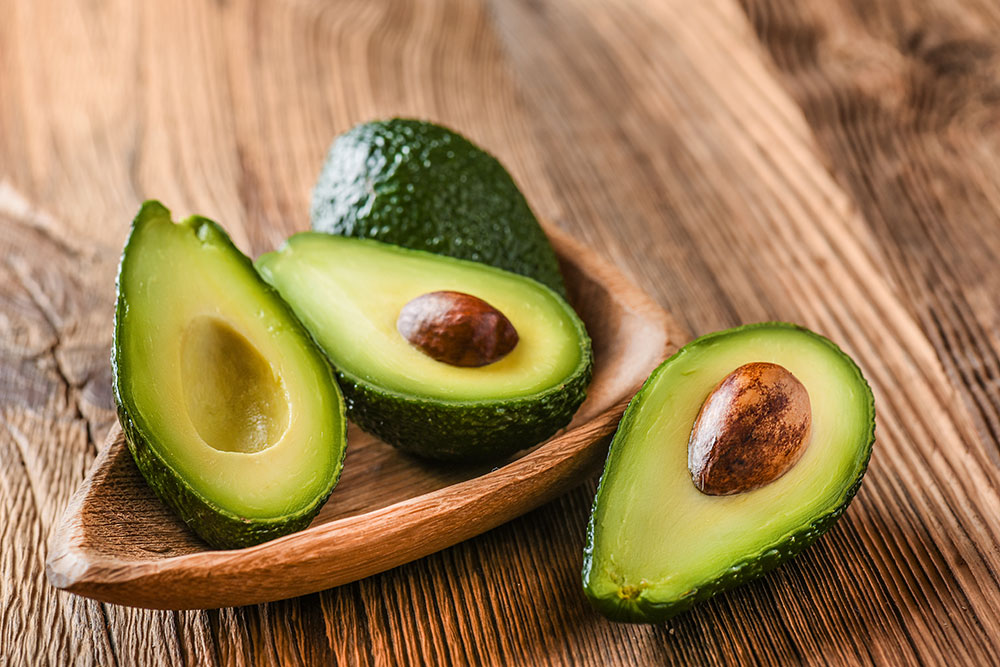 Avocado spread out on table, sliced in half