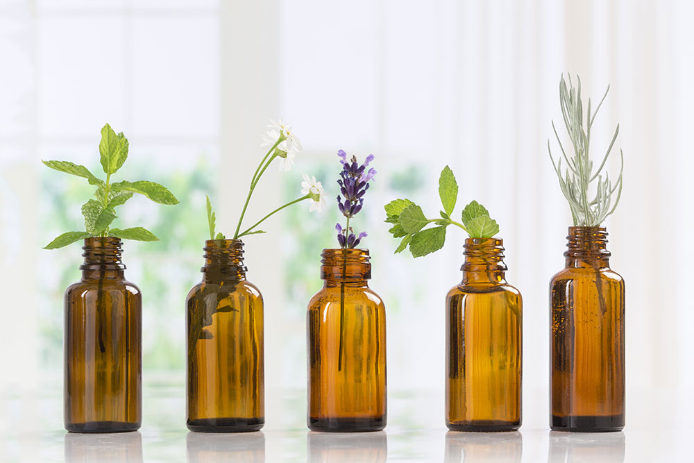 Tinctures of essential oils with herbs sticking out of them