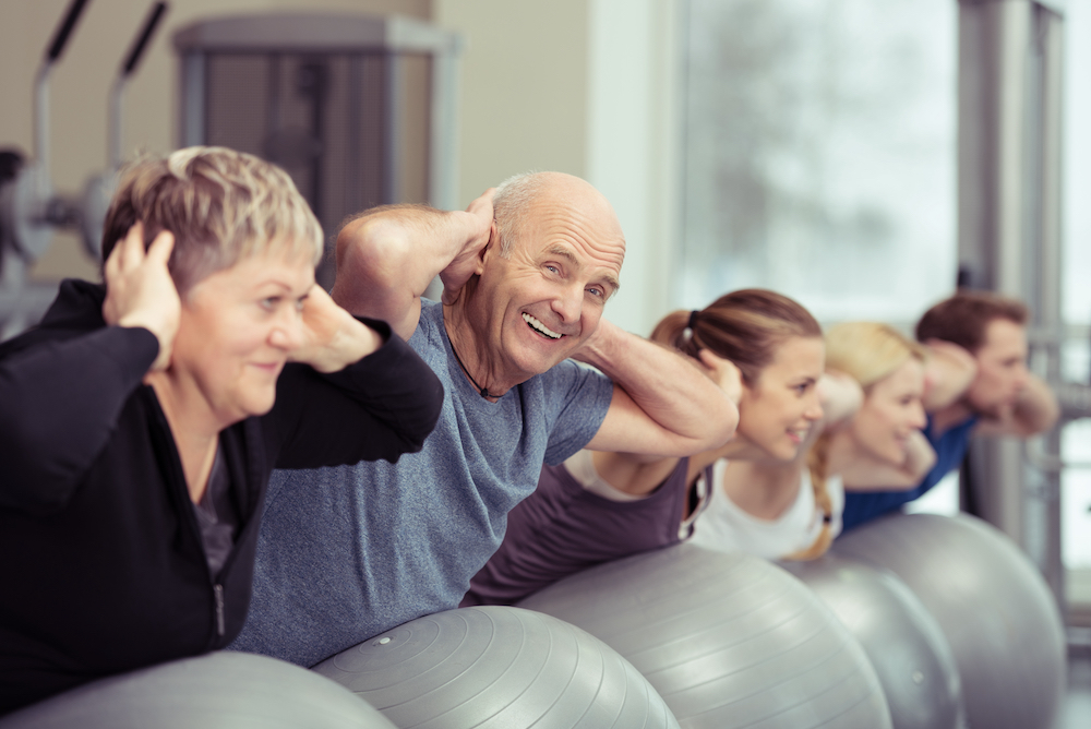 A senior man works out in a group fitness class