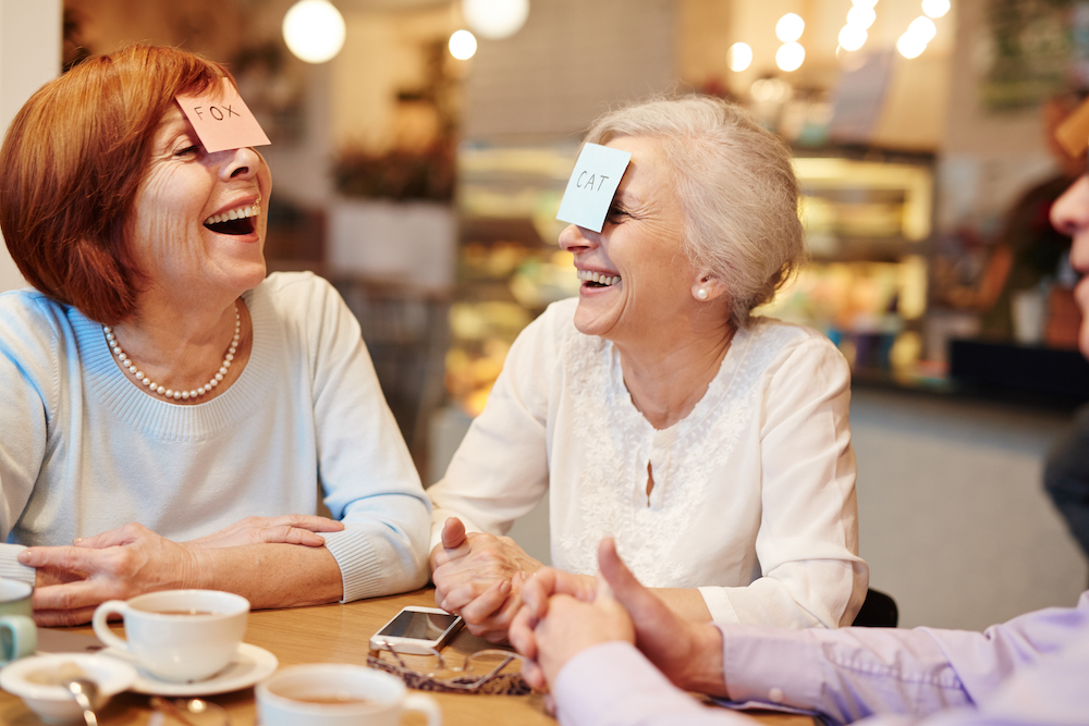 Two senior women play a game of 'Who Am I?'.