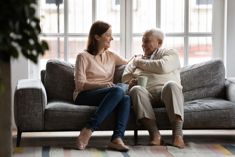 A senior man and his daughter talk on a sofa