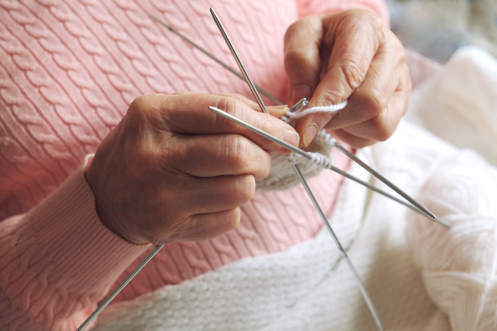 A senior woman knits a scarf