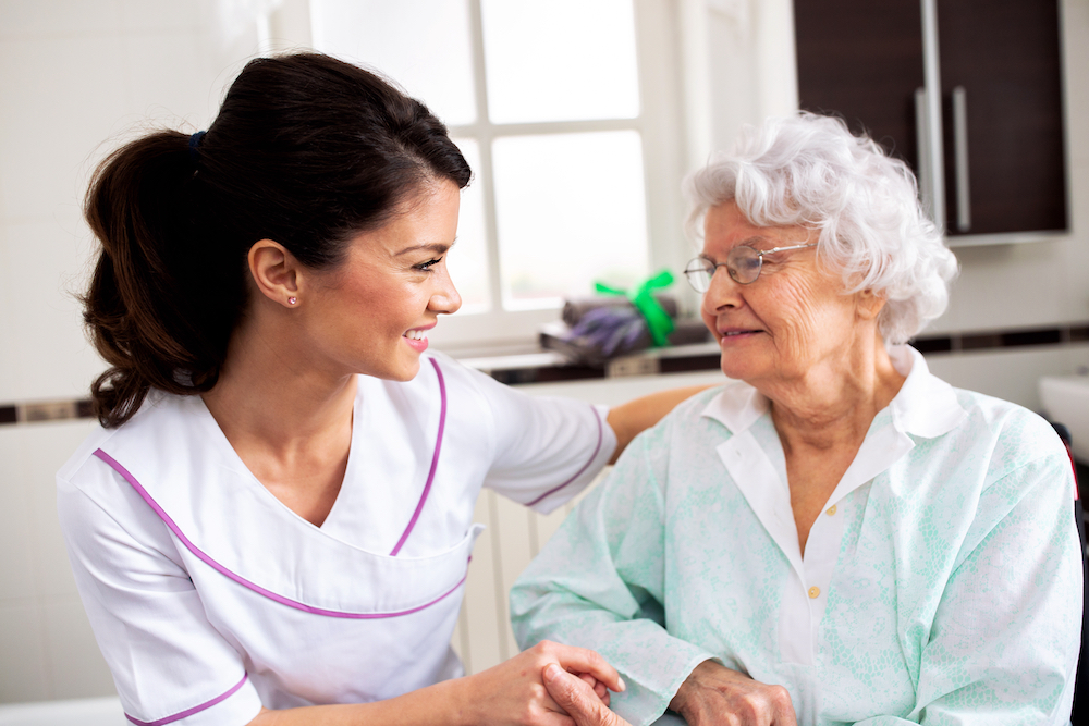 A senior woman and her caregiver smile together