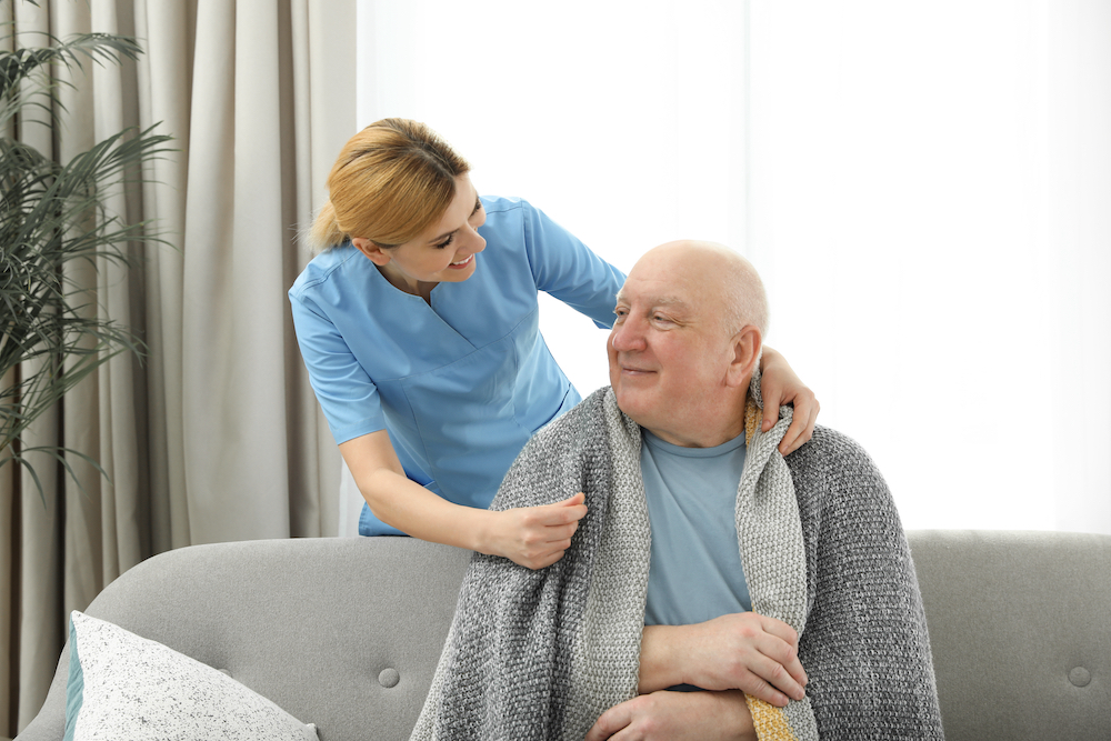 A nurse giving a senior man a blanket