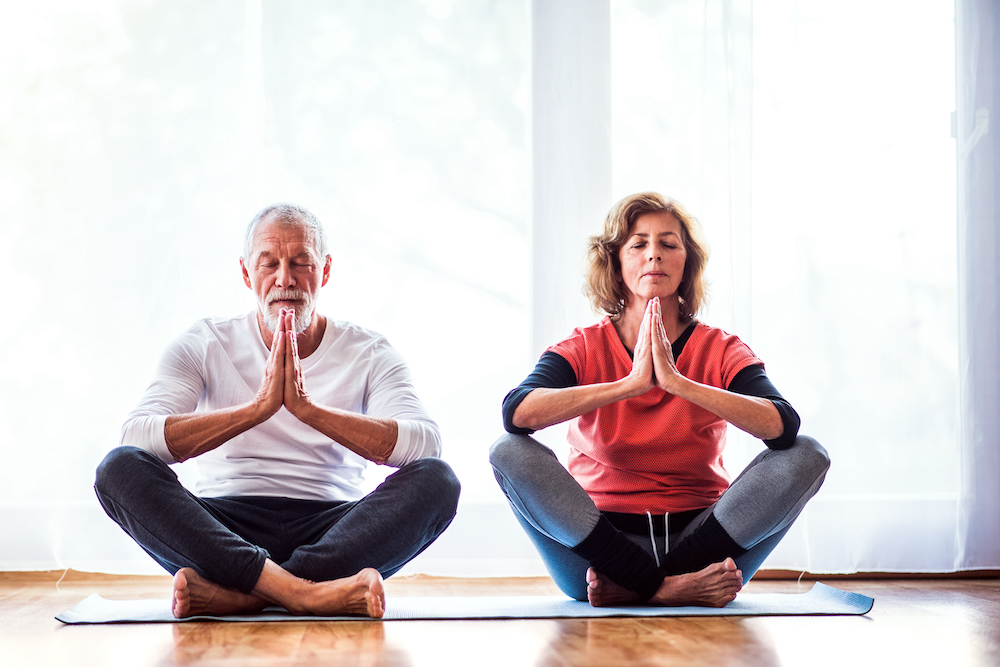 A senior couple does yoga together