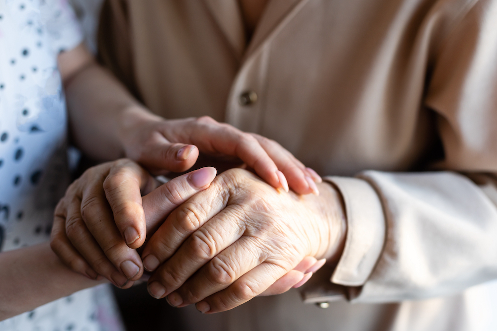 A senior man hold his caregiver's hand