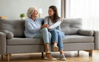 A senior woman and her daughter sit and talk in a living room