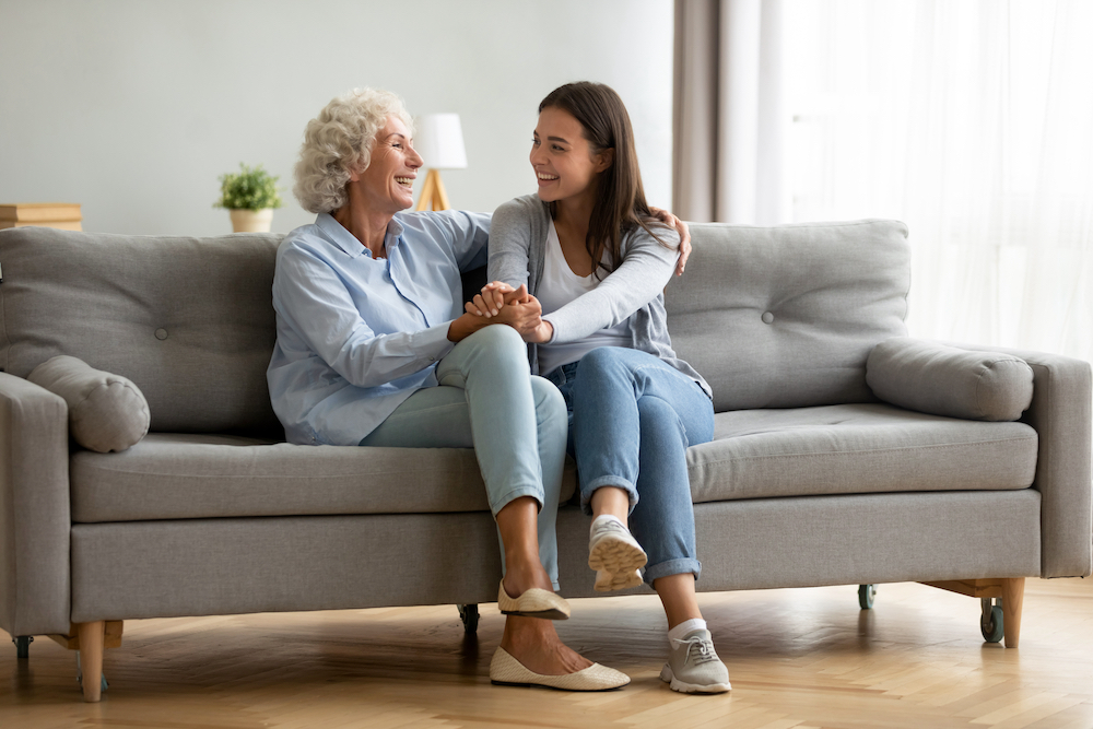 A senior woman and her daughter sit and talk in a living room