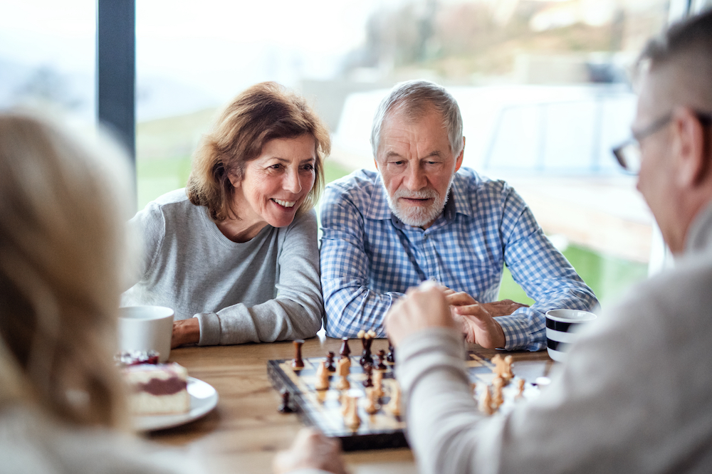 A group of seniors enjoy playing chess together in assisted living