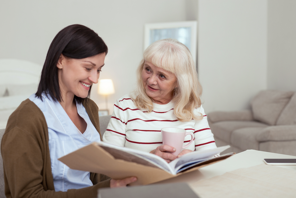 A senior woman and a caregiver looking through a photo album together