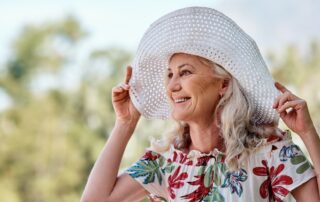 A happy senior woman enjoying the outdoors in a big summer sunhat