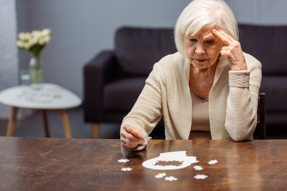 A senior woman struggles to complete a puzzle