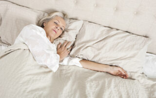 A senior woman sleeps in her bed