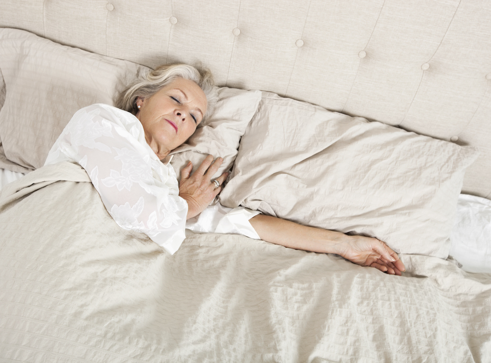 A senior woman sleeps in her bed