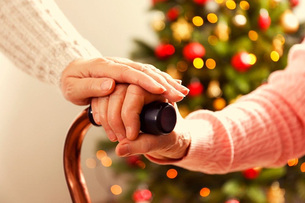 A senior woman and her caregiver hold hands while they discuss moving to the assisted living facilities in Macomb