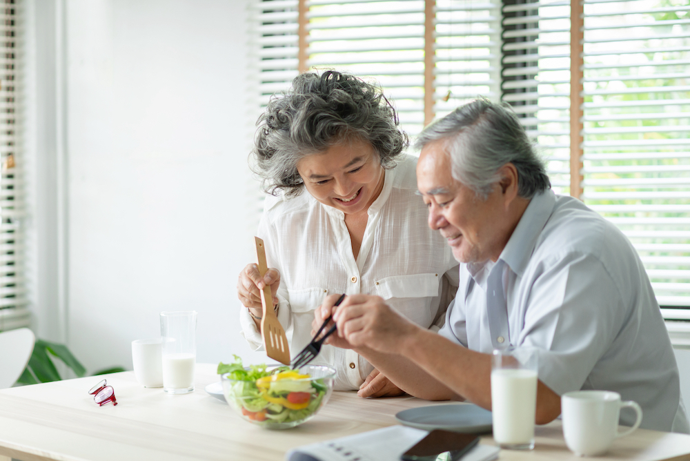 A happy senior couple eating a salad at the dementia assisted living facilities near me