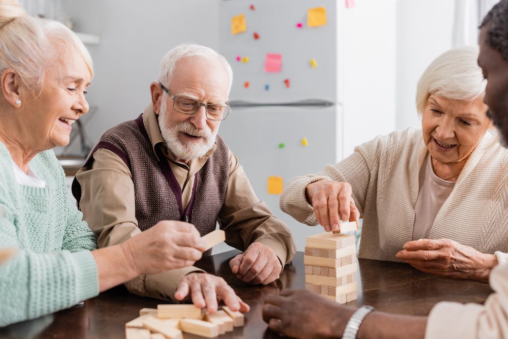 A group of four senior friends laugh and have fun while playing a board game together