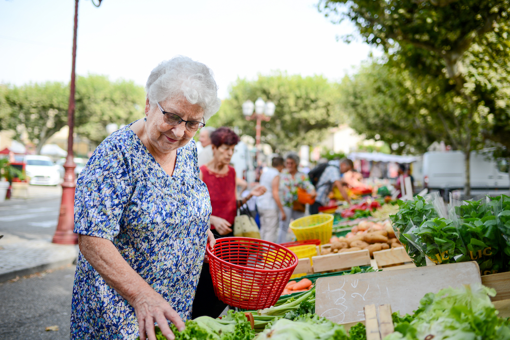 A happy senior woman shopping for fresh produce at an outdoor farmer's market