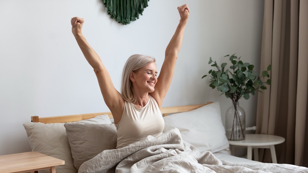 A senior woman waking up at the senior housing near me, stretching her arms