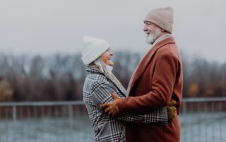 A senior couple laughing and sharing a hug while outdoors in the winter