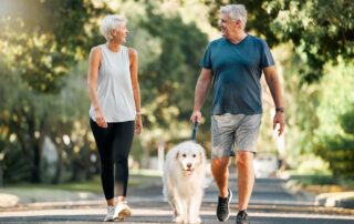 A fit senior couple going on a walk with their dog near the best senior living near me