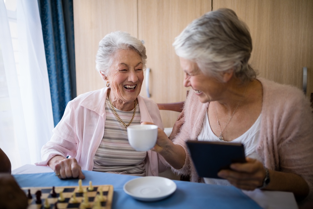 Two senior women having coffee and laughing
