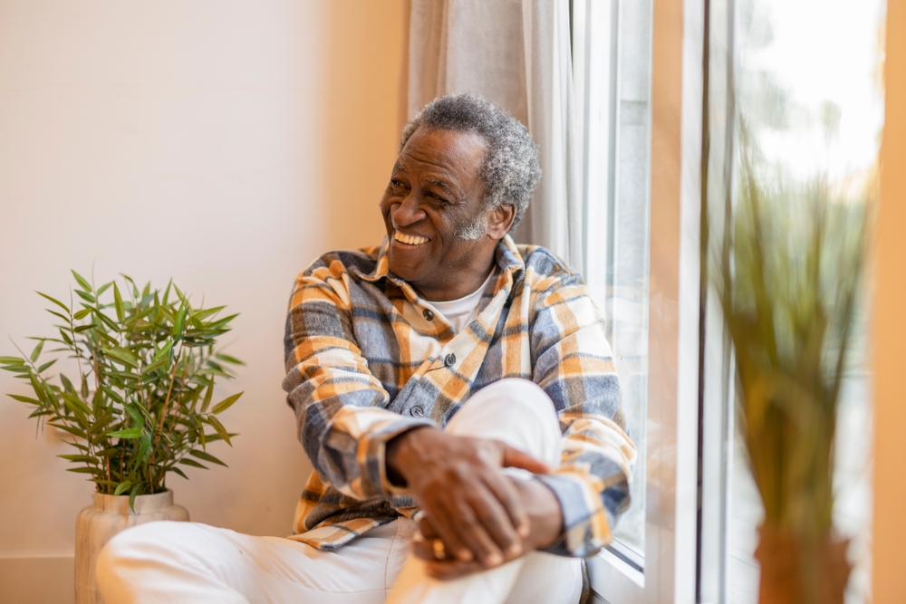 Man smiling by his window in senior living near me.