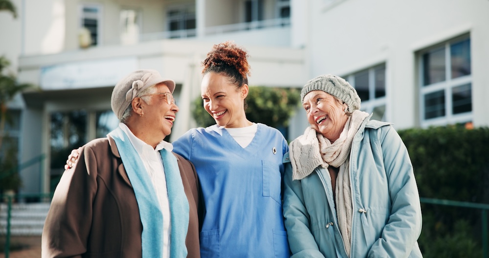 Two senior women enjoying the outdoors with a caregiver from memory care macomb mi