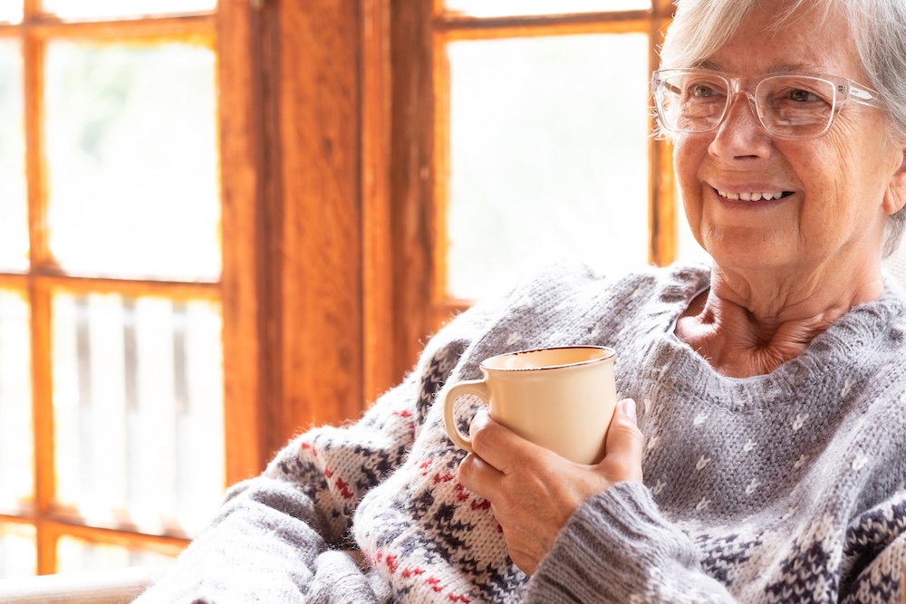 Senior woman indoors warm with a hot cup of coco enjoying the best assisted living in michigan