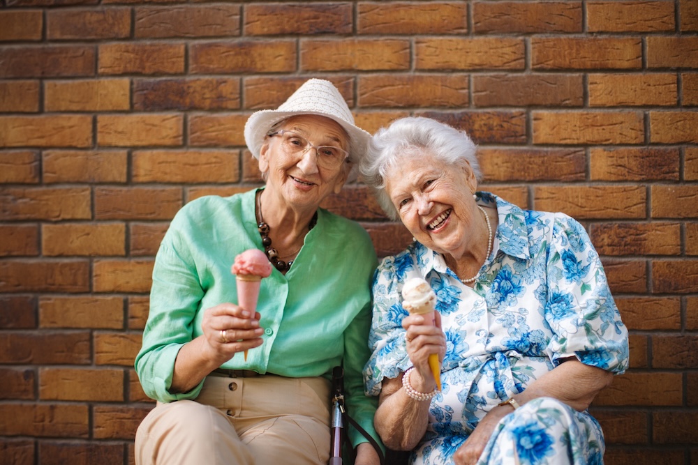 Two senior women friends enjoying ice cream and the vibrant lifestyle at dementia assisted living facilities near me